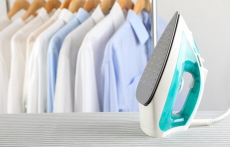 Ironed shirts hanging on a rail and an iron