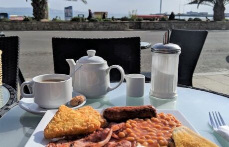 Full English breakfast on patio table facing seafront
